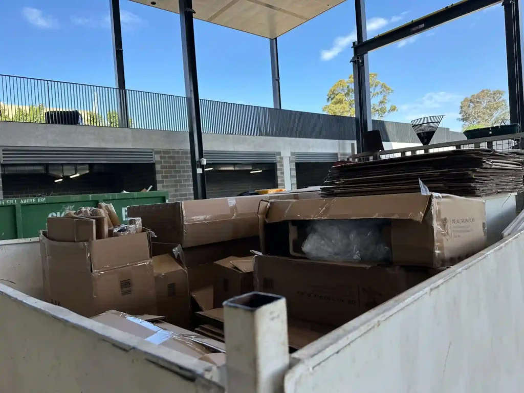 Cardboard boxes fill a skip bin at a warehouse, highlighting commercial rubbish removal.