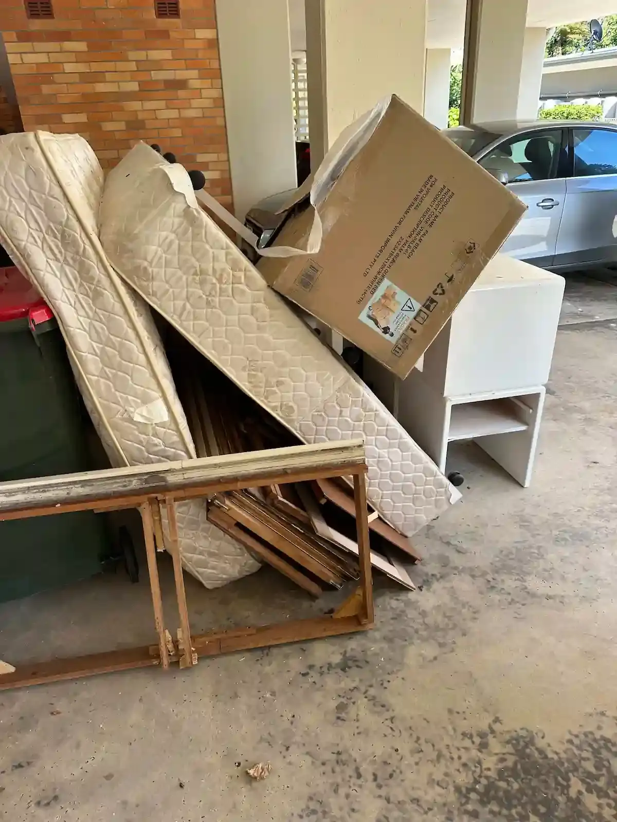 Team handling Deceased Estate rubbish, clearing mattresses and frames from a garage with care.