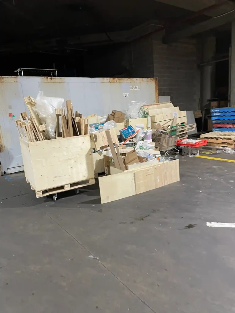 Stacks of excess timber and wooden planks placed in a showroom corner, ready to be collected and disposed of as part of commercial rubbish removal.