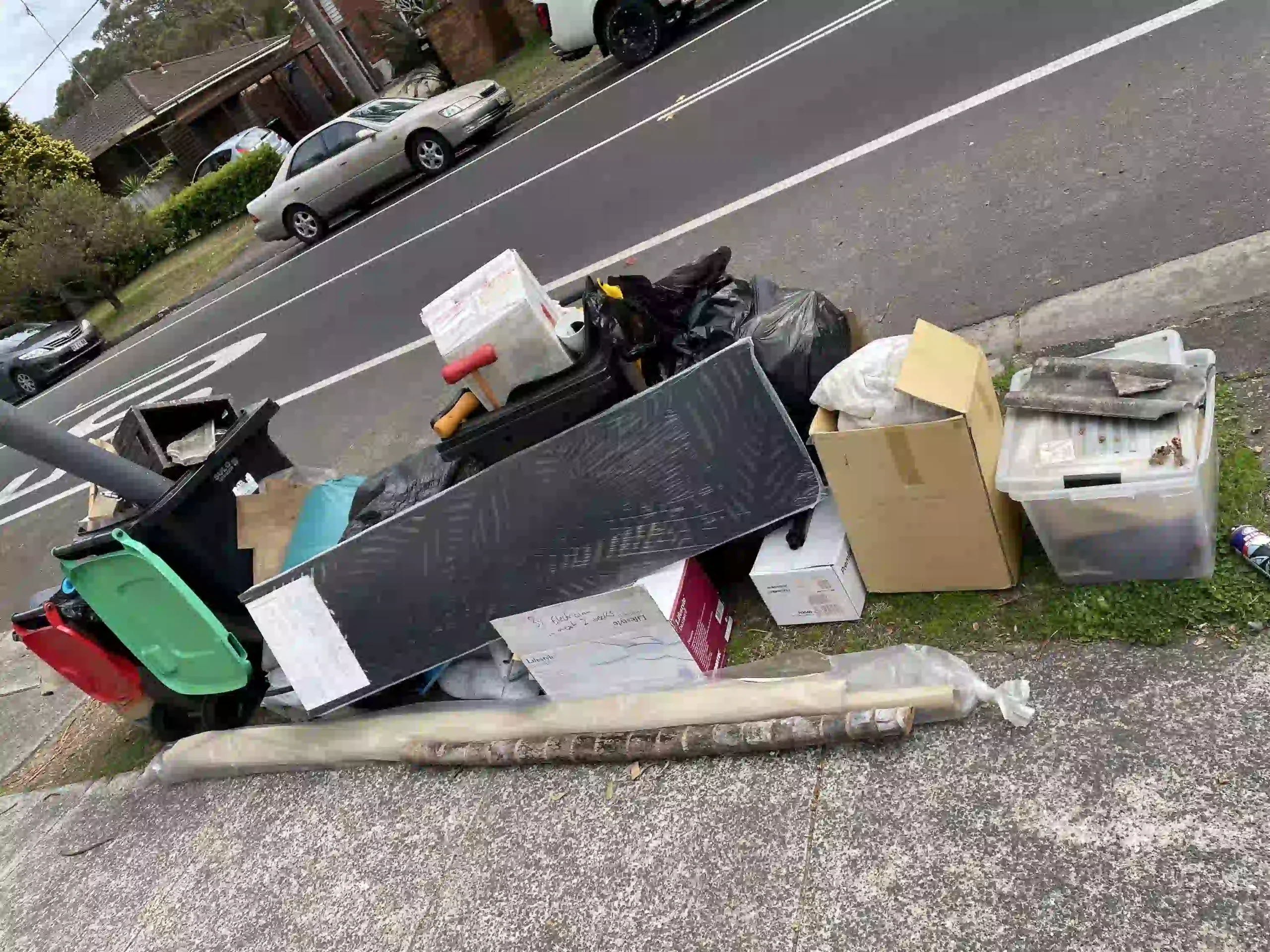 Pile of illegally dumped household waste on a suburban NSW street kerb.