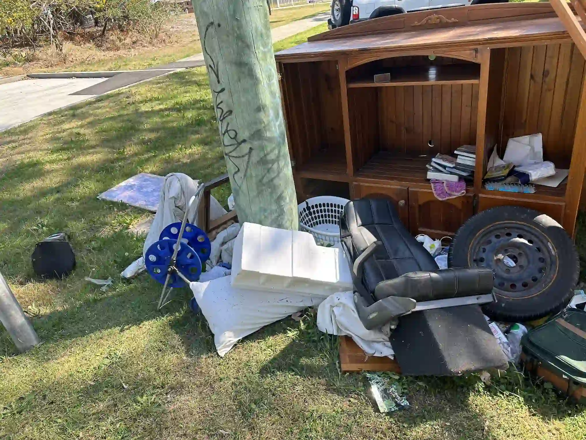 Deceased Estate rubbish dumped on a roadside in Central Coast, including old tyres, broken chairs, cupboards, and mixed household waste.