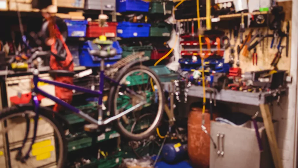 cluttered garage filled with tools, storage boxes and a bicycle before garage decluttering